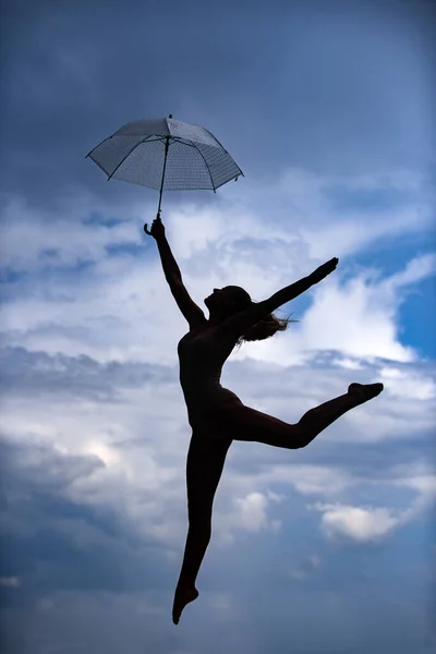 Silueta de mujer con paraguas haciendo estiramiento de ejercicio al aire libre. Estudio de danza. —  Fotos de Stock