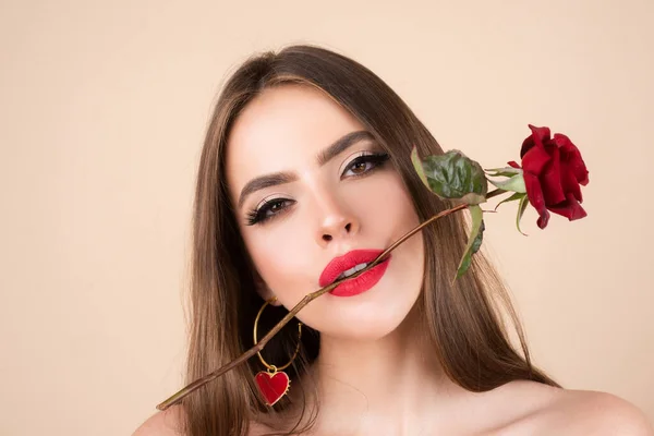 Zbliżenie świeżej twarzy dziewczyny. Brunetka z czerwoną różą. Piękna dziewczyna z kwiatami reses. Zbliżenie twarz młodej pięknej kobiety ze zdrową czystą skórą i jasny makijaż. — Zdjęcie stockowe