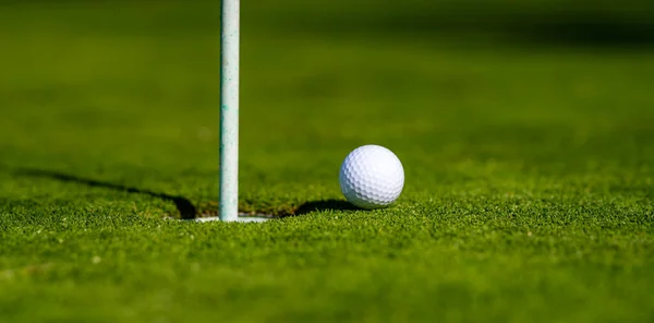 Pelota de golf en el labio de la taza en el fondo de hierba. Golf agujero. —  Fotos de Stock
