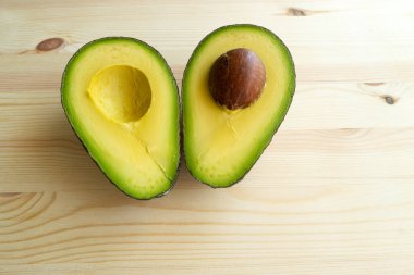 Avokado meyvesi. Çiğ meyveler sağlıklı yeşil yiyecekler. Yarım avokado. Ahşap zemin üzerinde avokado.