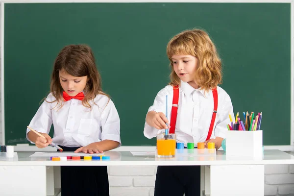 Skolbarn ritar färgglada bilder med pennkritor i klassrummet. Söta elever njuter av konst och hantverk lektion. — Stockfoto