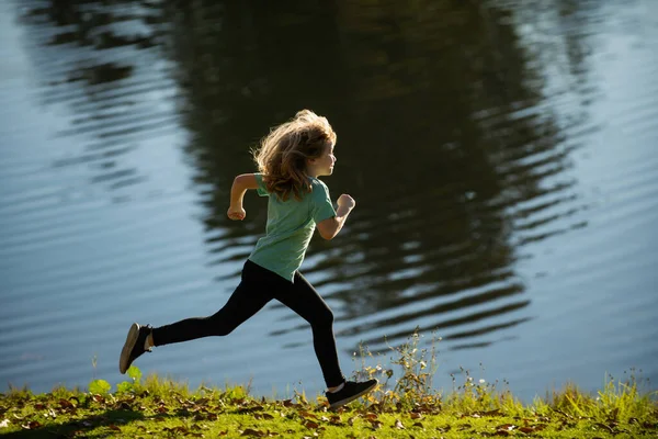 Kind läuft auf See. Glücklicher Kinderlauf im See in den Sommerferien. Sportliches Joggen und Training im Freien. — Stockfoto