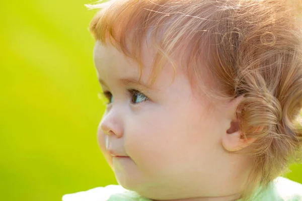 Cute baby face zbliżenie na zielonej trawie w okresie letnim. Zabawny portret małego dziecka na łonie natury. Szczęśliwego dzieciństwa. — Zdjęcie stockowe