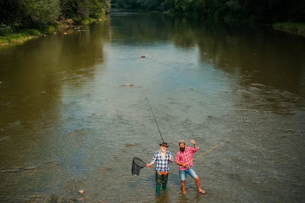 Deux hommes amis pêcheur pêche sur la rivière. Vieux père et fils avec canne à pêche au bord de la rivière. Activités récréatives. — Photo