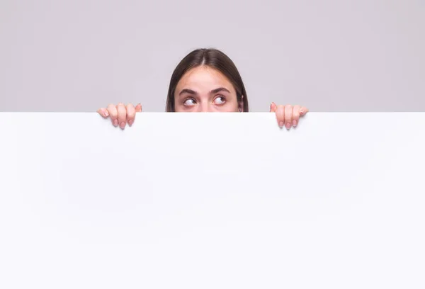 Girl pointing finger on blank board. Woman standing behind the white blank banner or empty copy space advertisement board. —  Fotos de Stock