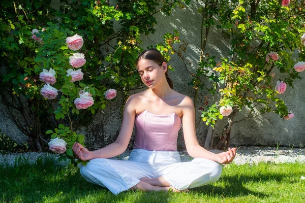 Mujer de yoga de meditación en el parque de primavera sobre hierba verde. Deporte fitness mujer estirándose antes del entrenamiento. Modelo de ajuste femenino. Estiramiento y motivación. Entrenamiento al aire libre. — Foto de Stock