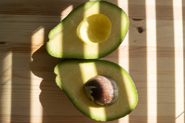 アボカドの実。生の果物健康的な緑の食品。アボカドの半分。木の背景にアボカド. — ストック写真
