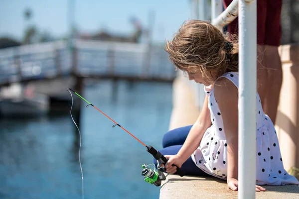 专心致志、严肃严肃的小女孩用钓竿钓到了一条鱼. — 图库照片