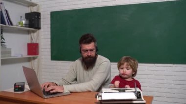 Daktiloya karşı dizüstü bilgisayar. Eski ve genç kavramları. Teknoloji kuşağı savaşı. Baba oğul gelişimi. Gençler yaşlı yetişkinlere karşı. Baba ve oğul eski daktilo ve dizüstü bilgisayarda yazıyor..