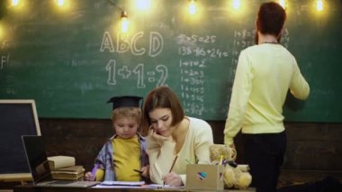 Ebeveynler çocuklara öğretiyor. Erken gelişim kavramında aile. Baba, anne ve çocuk evde birlikte resim yapıyorlar. İlkokuldaki öğrenci çocuklar..