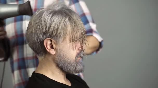 Frisör med hårtork gör hår av snygg skäggig man klient i professionell frisör salong, frisör. — Stockvideo