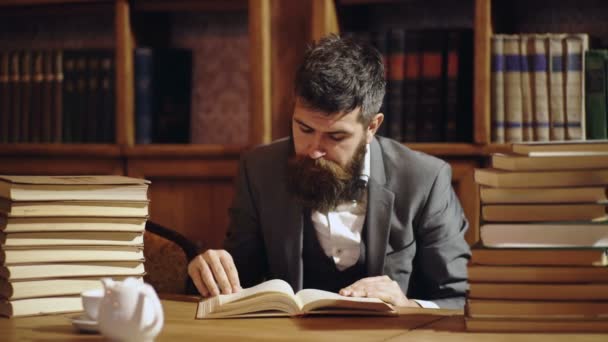 Man reading book in classical library cabinet. Home library. Businessman sits in vintage interior, holds book. Business man in suit in his cabinet. Mature man with calm face enjoys reading. — стоковое видео