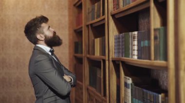 Eski kütüphanedeki konsantre adam. Klasik klasik iç mimari. Hukuk ve adalet kavramı. Adam kütüphanede kitap seçiyor..