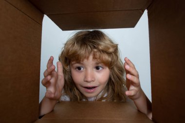 Çocuk bir kutu açıyor ve içine bakıyor, paketleri açıyor, sürpriz bir şekilde boks yapıyor. Çocuklar şaşırmış yüz ifadeleri.