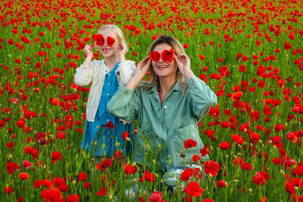 Mother with daughter on the poppies meadow. Beautiful mom and daughter on a poppy field outdoor. Poppies flowers. Happy motherhood. — Foto Stock