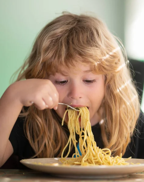 Lezzetli yemekler, spagetti yiyen dağınık çocuklar. Masada oturan genç çocuk yüzünde komik bir ifadeyle sağlıklı yiyecekler yiyor.. — Stok fotoğraf