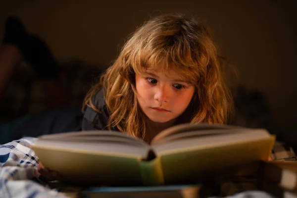 Barn läser en magisk bok i sängen. Grabben läste böcker hemma. Barnets utveckling. Smart pojke med barn. — Stockfoto