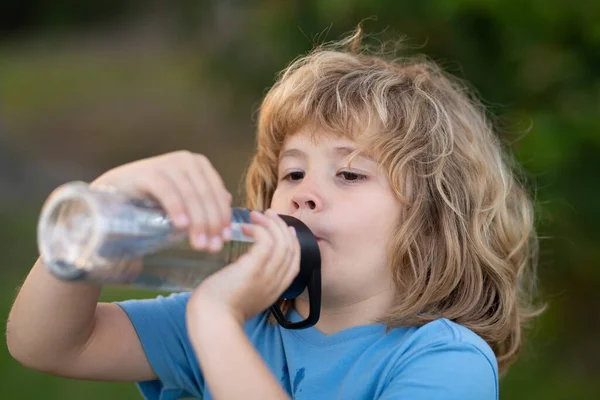 Child drinking water from bottle outdoor in park. Kid drinking. — Foto Stock
