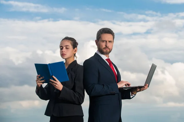 Business couple, professional occupation. Portrait of two freelancer outdoor. Secretary and boss. Business people in suit on sky. Man hold laptop woman with notebook. — Fotografia de Stock