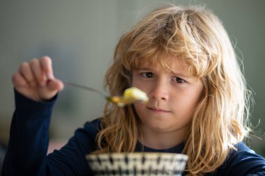 Komik bir çocuğun yemek yediği portreyi yakından çek. Üzgün çocuk öğle yemeğinde sağlıklı tavuk çorbası içiyor. Mutsuz bebek evde yemek yiyor, kreşe gidiyor, anaokuluna gidiyor..