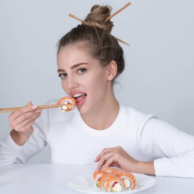 Japon suşi tarzı. Seksi kadın geleneksel Japon suşi ruloları yiyor. Kızın elinde yemek çubuklarıyla Japon suşisi rulo Philadelphia 'sı var..
