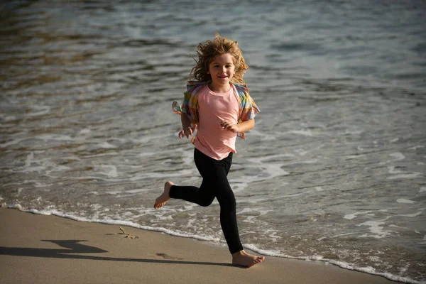 Niño corriendo a través del agua cerca de la orilla a lo largo de la playa. Un niño corre a lo largo de la costa. Resto de niños en vacaciones de verano. Pequeño atleta en entrenamiento. Ejercicio de corredor, correr para niños. —  Fotos de Stock