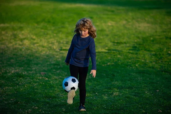 Młody piłkarz w odzieży sportowej z piłką nożną. Mały chłopiec strzelający do bramki, dzieciak kopiący piłkę nożną. — Zdjęcie stockowe