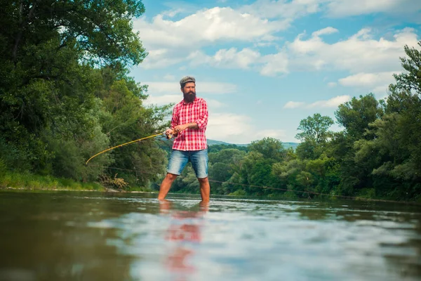 Fisherman fishing on a rever. Relaxed fisher man with a fishing rod on a summer day. — Stock Photo, Image