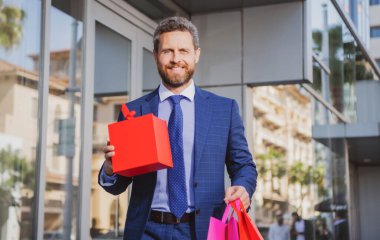 Alışveriş çantalı bir iş adamı. Yakışıklı, kendine güvenen bir iş adamı portresi..