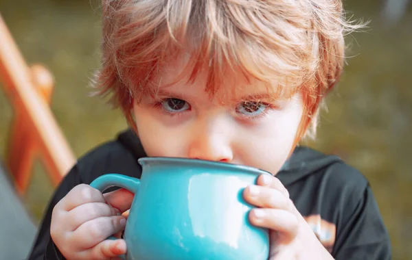 Chłopak coś pije. Małe dziecko bawi się na świeżym powietrzu. Portret uśmiechniętego chłopca na tle natury. — Zdjęcie stockowe