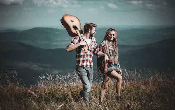 Dağlarda tatlı bir uyum. Mutlu gezginler yürüyüş yapar, gülümser ve gitar çalar..