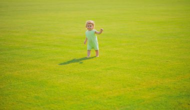 Tatlı komik erkek çocuk emeklemeyi öğreniyor, bahçede çimlerde oynarken eğleniyor..