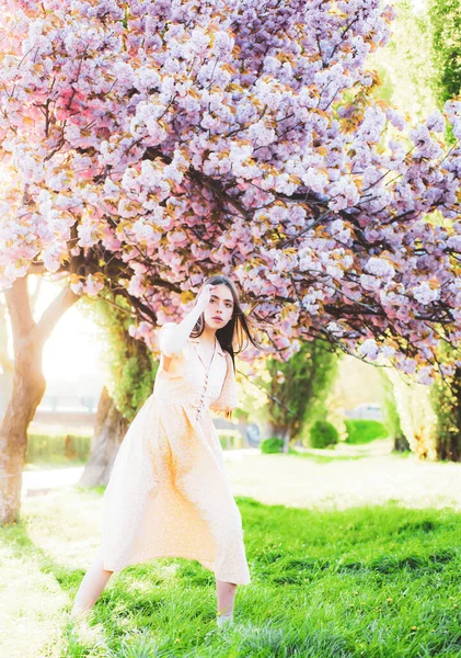 Mooi meisje in kersenbloesemtuin op een lentedag. Bloesem kersenboom, sakura. — Stockfoto