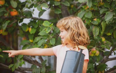 Çocuk bahçede çalışıyor, çiçekleri suluyor..