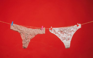 Külotlar kırmızı üzerine izole edilmiş. Kadın dantelli külot. İpe asılı erotik külotlar. Çamaşır ipinde kadın iç çamaşırı. Renkli erotik külot. Kadın iç çamaşırı.
