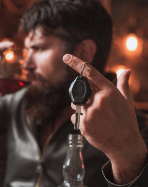 Sakallı adam cam brendi tutar. Maço içkisi. Elinde araba anahtarları olan kendine güvenen bir adam. İçki içmeyin ve araba anahtarları konuşan sarhoş adam Kırpılmış görüntü sürücü.
