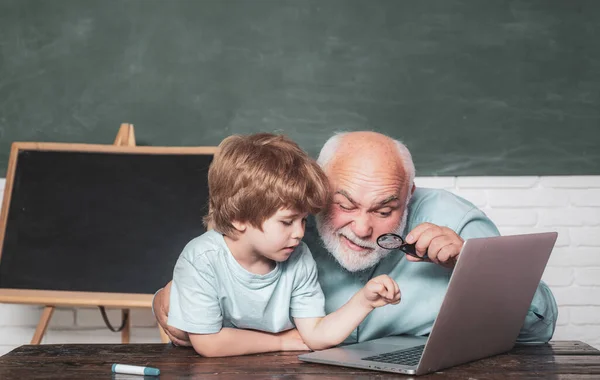 Portrét sebevědomého starého učitele. Dědeček mluví s vnukem. Vzdělávání a učení lidé koncept - malý student chlapec a učitel pomocí notebooku. Starý a mladý. — Stock fotografie