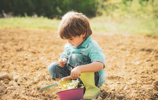Ung bonde. Toddler jobbar i blomsterparken. Jorddagen. Barnbonde på gården med lantlig bakgrund. — Stockfoto