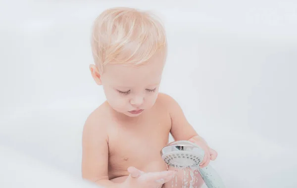 Прекрасна дитина грає з піною. Чарівна блондинка малюк розважається з водою, приймаючи ванну у ванній . — стокове фото