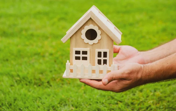 Agente imobiliário, casa de madeira em mãos masculinas. Mão segura modelo de casa de brinquedo, compra ou aluguel de casa. — Fotografia de Stock