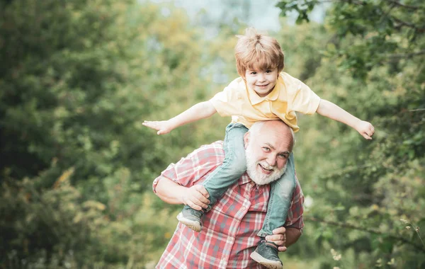 Niño feliz jugando con alas de juguete brazos contra el fondo del cielo de verano. Abuelo y nieto jugando - Tiempo en familia juntos . — Foto de Stock