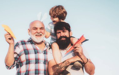 Uçmayı hayal et. Mutlu çocuk dışarıda oynuyor. Mutlu gülümseyen çocuk, baba kameraya bakıyor. Erkek çok nesilli aile.