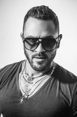 Güneş gözlüklü yakışıklı bir adam. Erkek yüzü. Yakışıklı, erkeksi bir adamın portresi. Gri duvara karşı memnun iş adamının portresi. Güneş gözlüğü. Şehir modası.