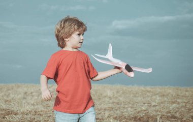 Gün batımında oyuncak uçağı olan küçük çocuklar. Başarı ve çocuk lider konsepti. Çocuk pilot olmayı hayal ediyor. Güneşli bir yaz gününde altın buğday tarlasında yürüyen tatlı bir çocuk..