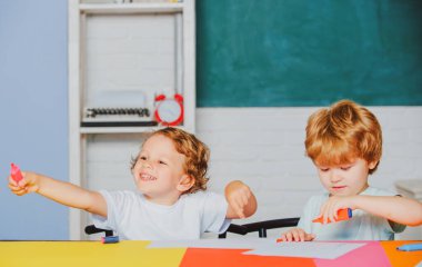 Neşeli gülümseyen çocuklar tahtaya tırmanıyor. İlkokuldan bir çocuk..