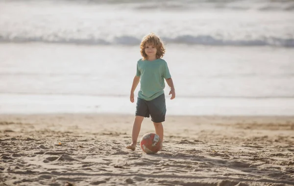 Grabben spelar fotboll på sandstranden. — Stockfoto