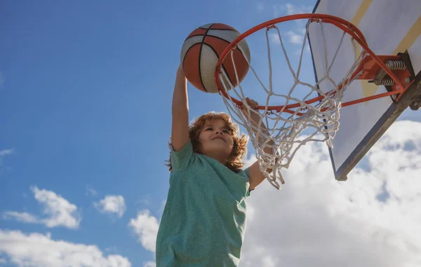 Aktiva barn njuter utomhus spel med basket. Basket barn spelare som springer upp och doppa bollen. — Stockfoto