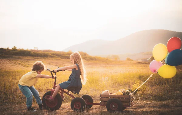 Güneşli bir günde gülümseyen küçük çocuklar. Dışarıda poz vermek. Balonlarla. Anın tadını çıkar. Mutlu küçük çocuklar gülümsüyor. Çocuk bakımı. Küçük kız ve oğlan hayatın ve doğanın tadını çıkarın..