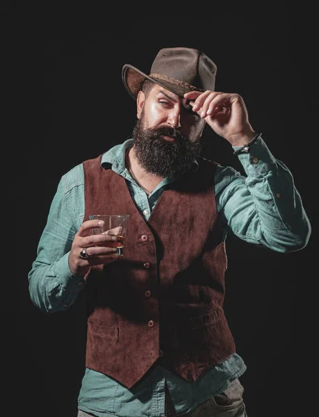Homme barman avec barbe tient verre brandy. Homme barbu confiant en costume noir avec verre de whisky en mezzanine. Boisson alcoolisée . — Photo