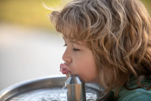 Child drinking water from a water fountain in park. — стоковое фото